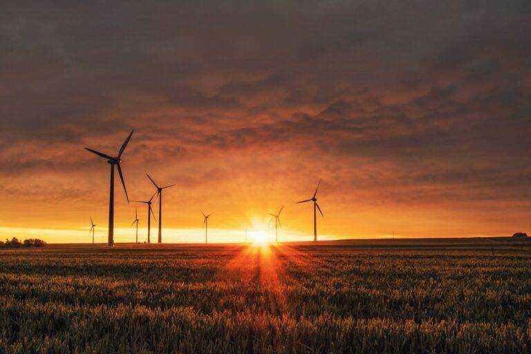 "Západ slunce nad větrnými elektrárnami symbolizuje udržitelný rozvoj a integraci obnovitelných zdrojů energie v rámci místní energetické koncepce a akčního plánu pro udržitelnou energii a klima. Obrázek zdůrazňuje důležitost plánování, které podporuje energetickou soběstačnost, snižuje uhlíkové emise a zajišťuje harmonii mezi technologií a přírodou.